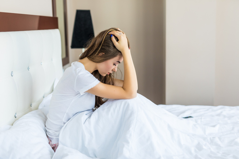 Stressed women sitting up in bed with hands on head