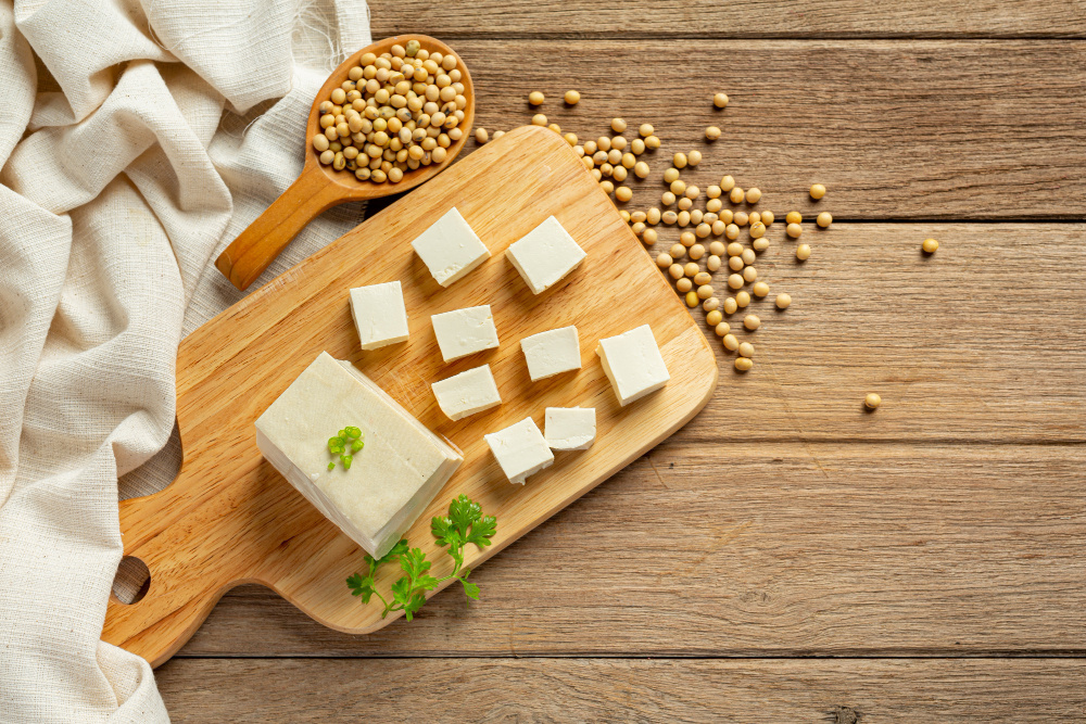 Block of tofu cure into cubes on wooden chopping board