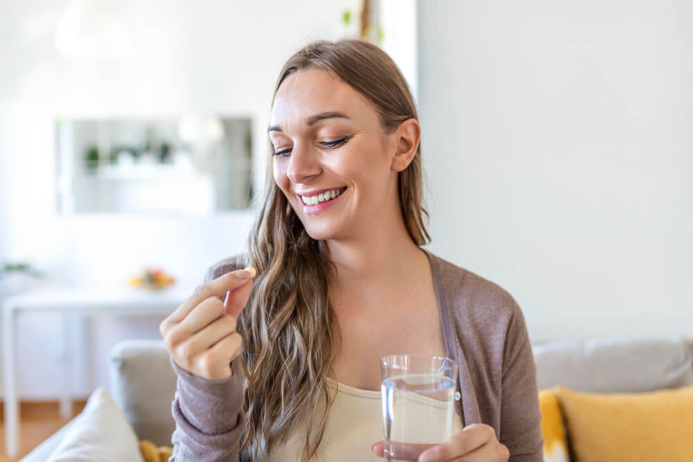 happy-woman-holds-supplement-with-glass-of-water