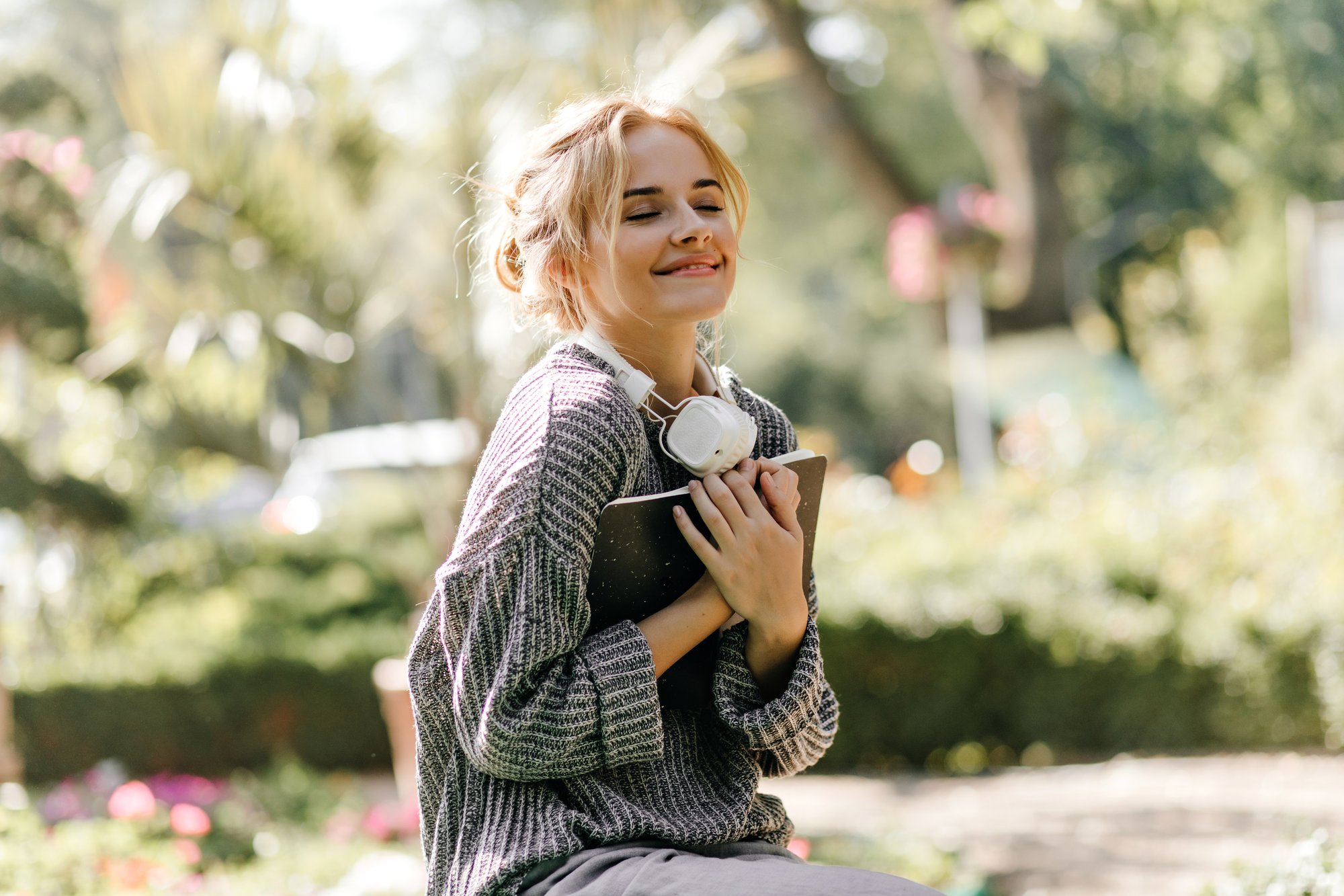 close-up-portrait-woman-sitting-greenhouse-with-headphones-book