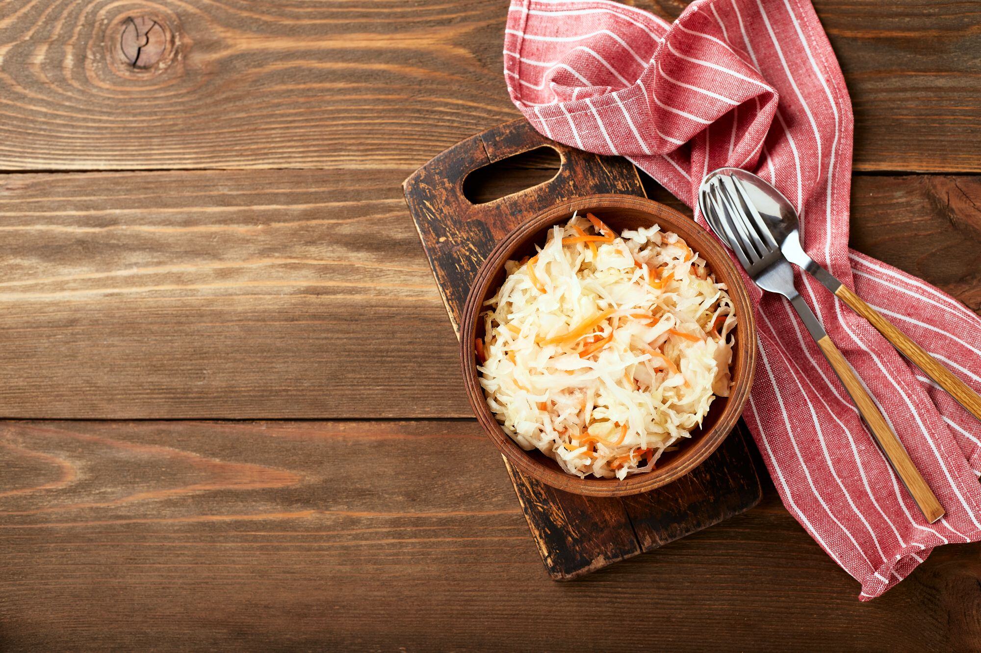 sauerkraut-fermented-cabbage-with-carrots-bowl-wooden-background-with-copy-space-superfoods-support-immune-system-top-view-flat-lay reduced