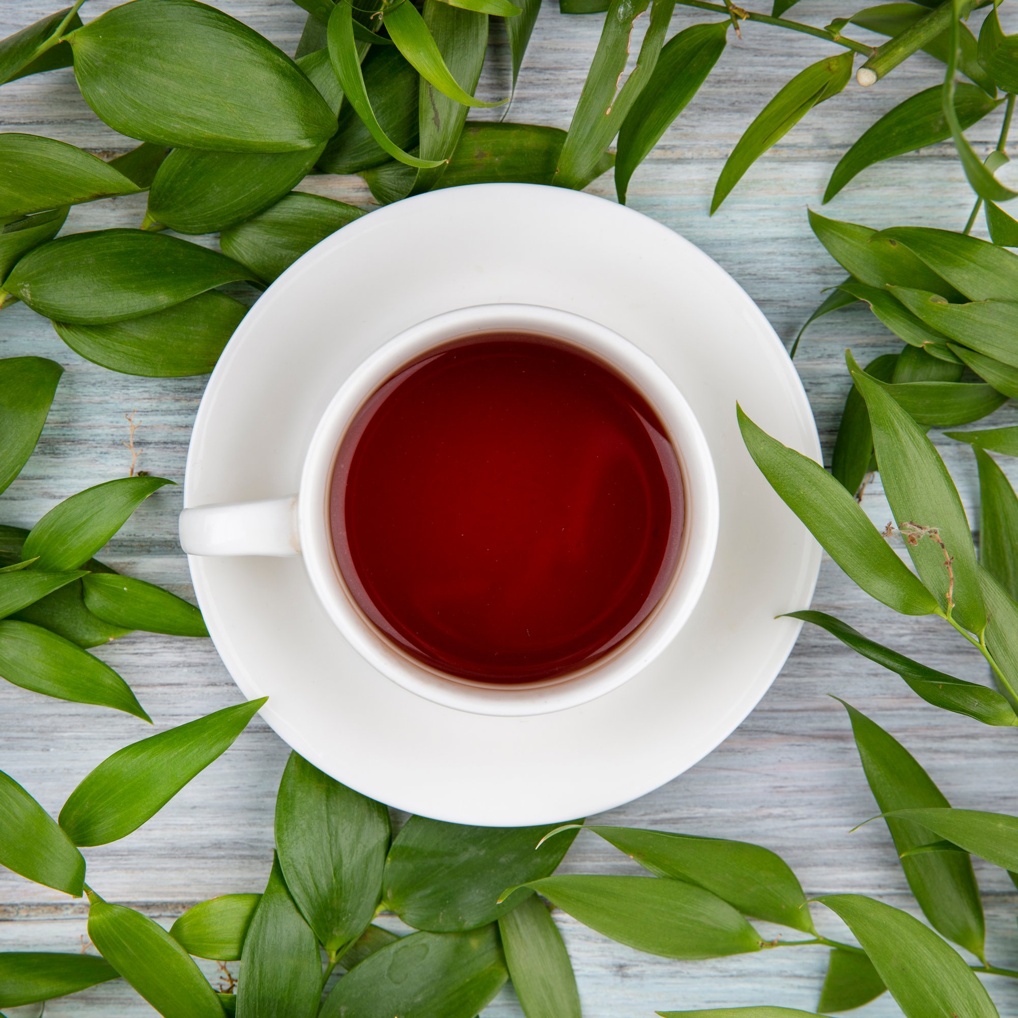 top-view-cup-tea-with-green-leaves-grey-wood