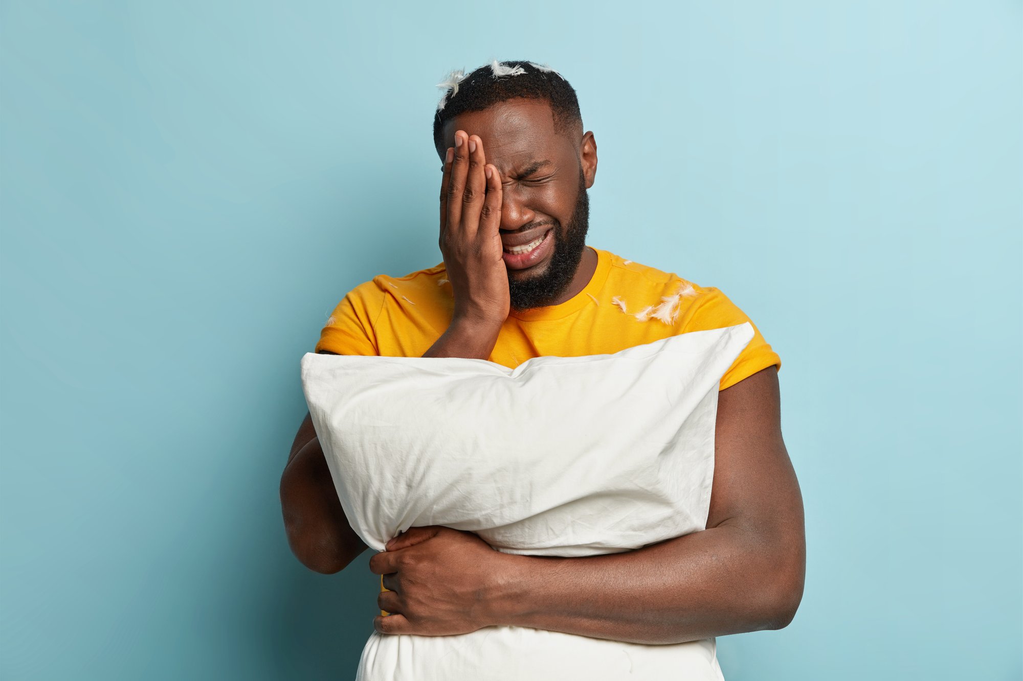 young-man-with-feathers-t-shirt-holding-pillow