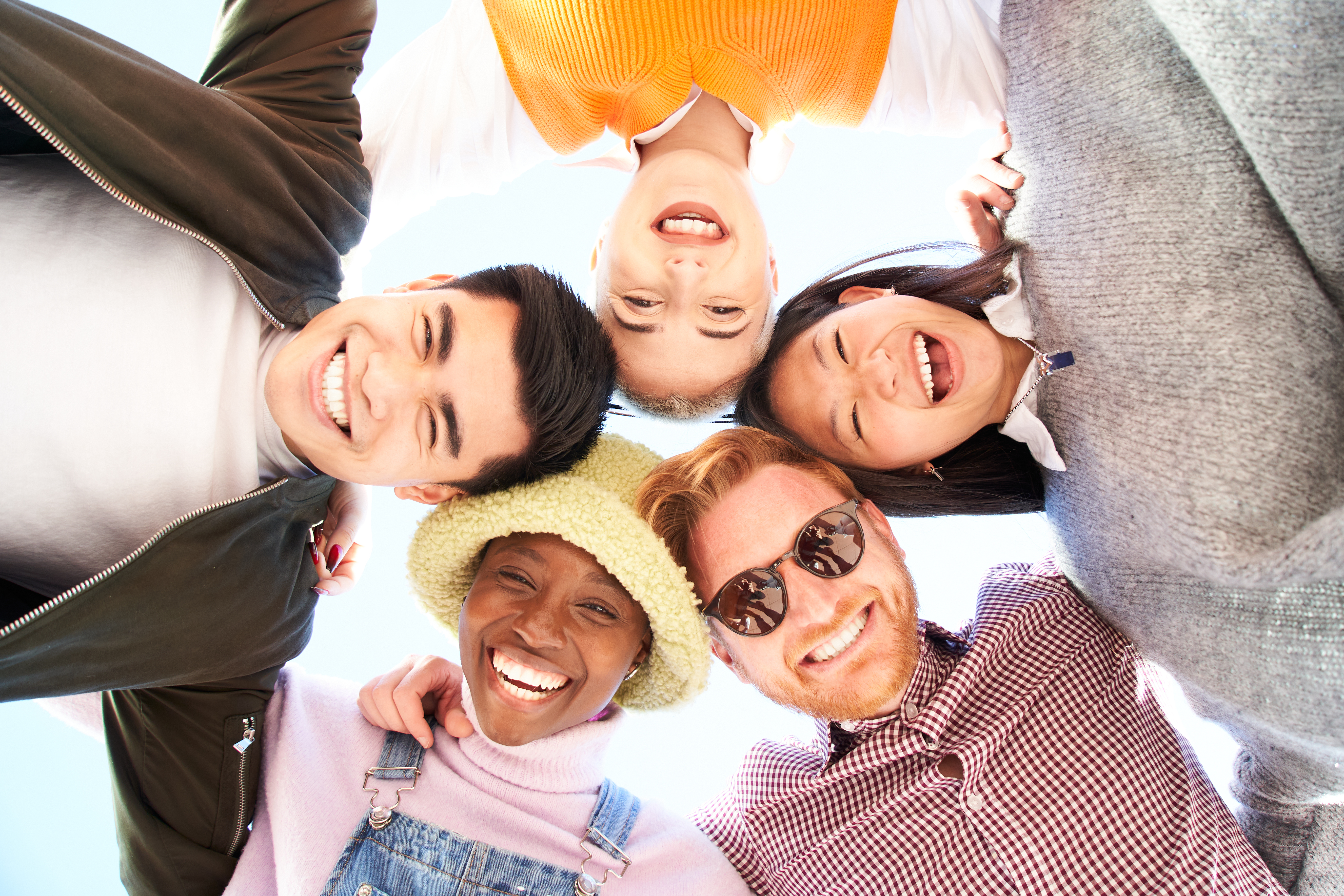 multiracial-diverse-group-friends-hugging-circle-looking-down-camera